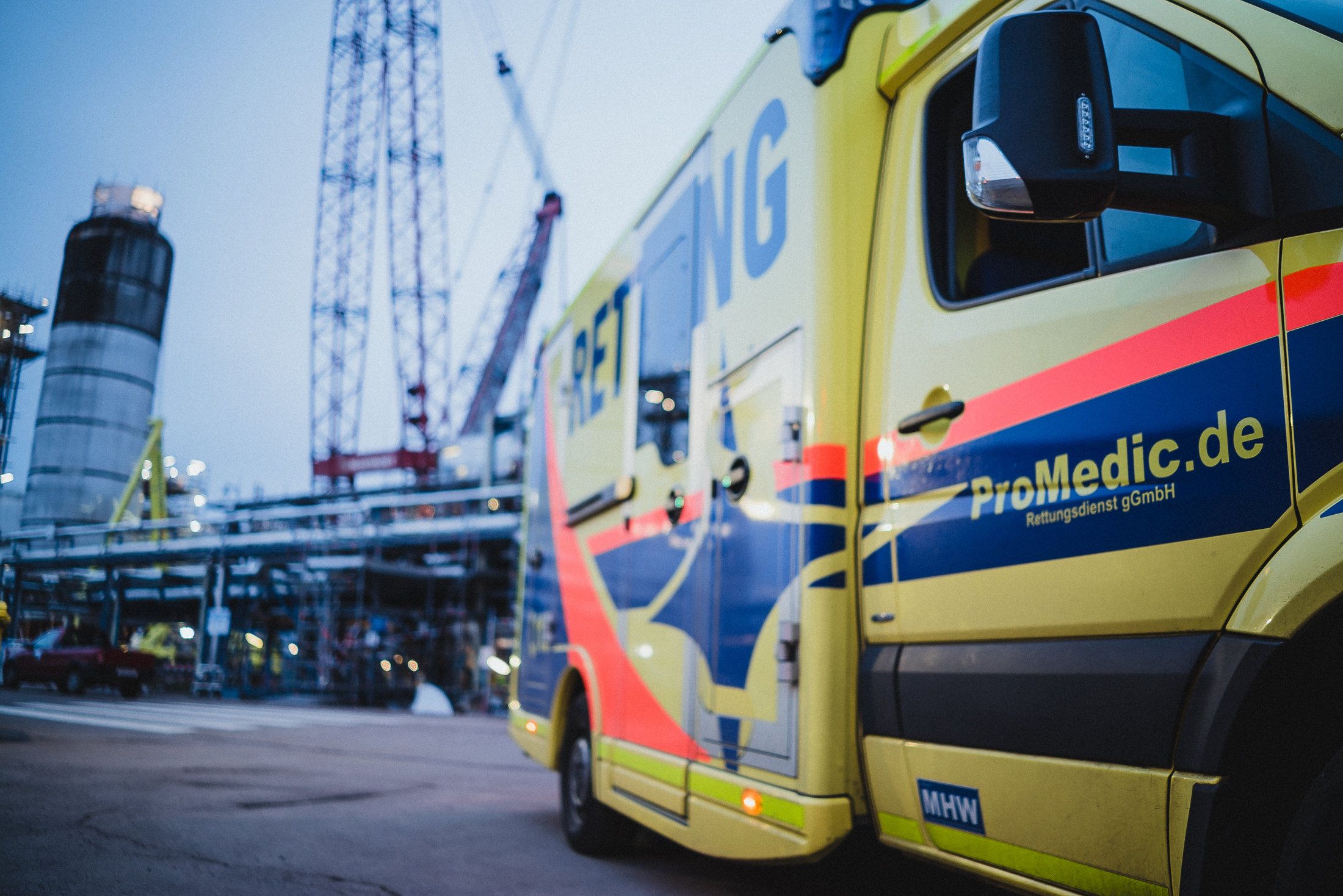 ProMedic-Rettungswagen vor einer Industrieanlage mit Kränen